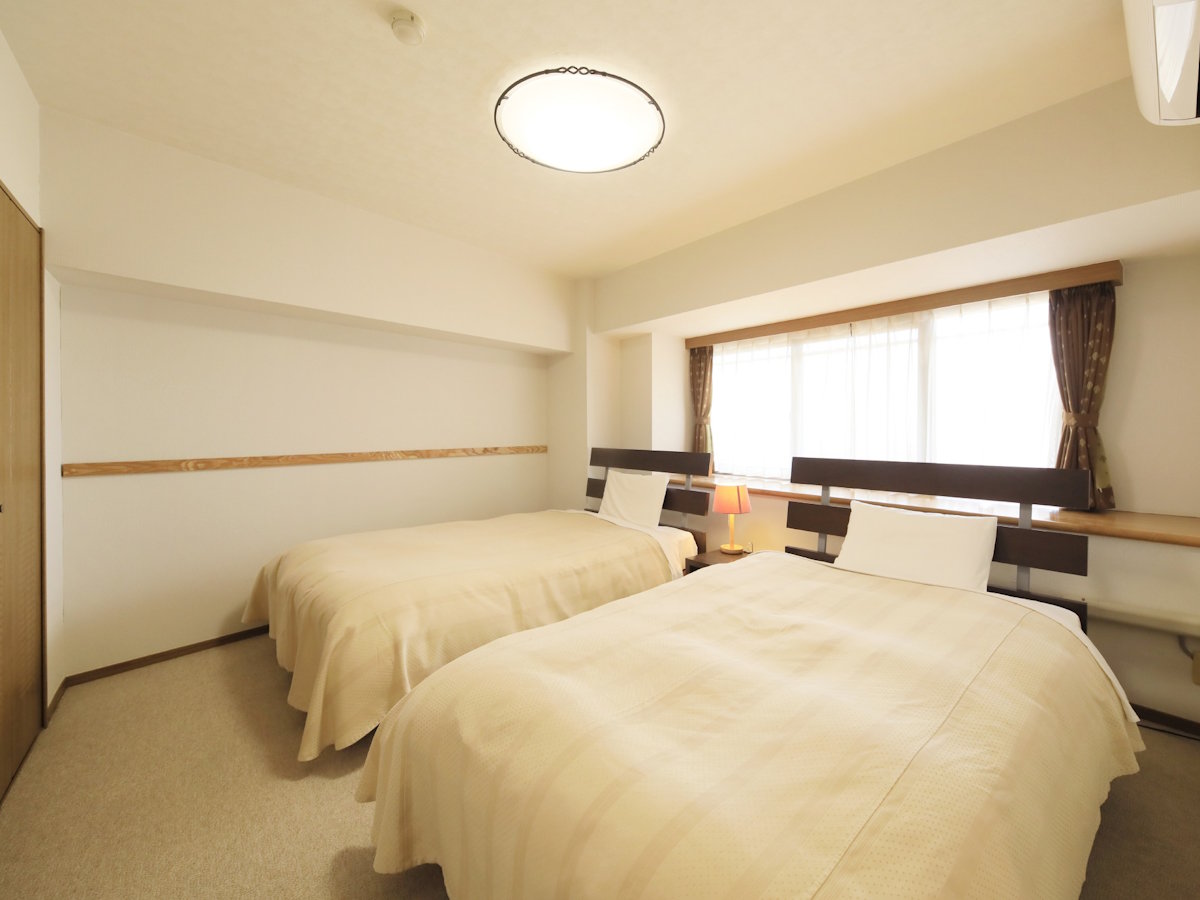 【デラックスルーム一例】セミダブルベッド2台の寝室。